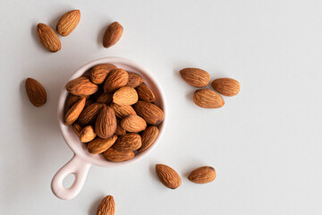 Fresh almonds nuts in pink plate on a white background. Flat lay, top view, copy space.