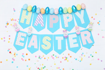 Text Happy Easter with colorful eggs and sprinkles on wooden table