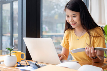 Young collage student using computer and mobile device studying online.