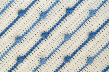 Crochet product from multicolored threads. Handmade backdrop. Flat lay. Fragment of a plaid of blue and ivory tone. Striped, geometric pattern. 12 ball