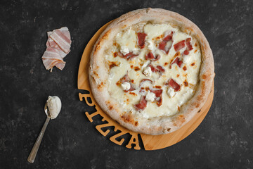 Homemade pizza with bacon cream sauce, mozzarella and ricotta on a dark background. Top view, side view