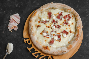 Homemade pizza with bacon cream sauce, mozzarella and ricotta on a dark background. Top view, side view