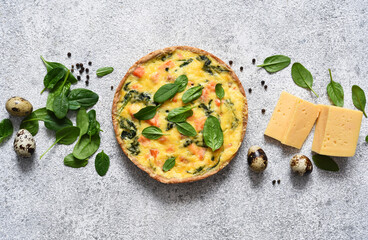 Quiche with salmon and spinach, cheese on a light concrete background. View from above.
