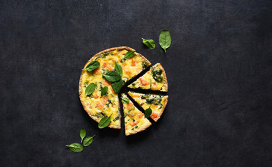 Tart with salmon and spinach, cheese on a black concrete background. Quiche with fish.