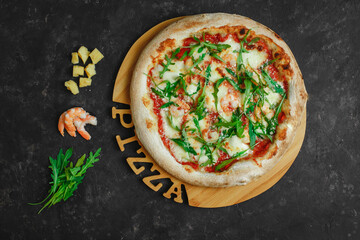 Homemade pizza with prawns. Tomato sauce, mozzarella, tiger prawns, parmesan and arugula on a dark background. Top view, side view