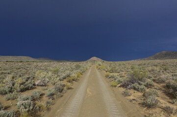 dirt road in the Karoo with a rain storm approaching in the background