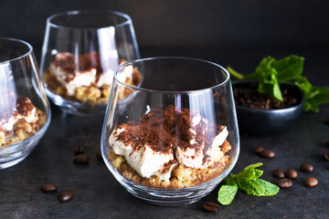 Dessert tiramisu in a glass on a dark concrete background.