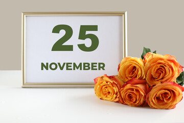 day of the month 25 November calendar photo frame and yellow rose on a white table
