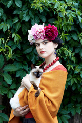 Girl brunette with red lips and a wreath of peonies on his head with cat