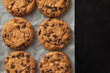 Crispy oatmeal cookies with chocolate on baking paper. Homemade cakes.