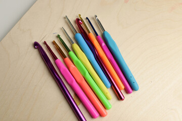 colored crochet hooks on wooden background
