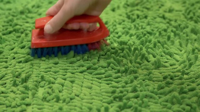 Female Hand Cleaning Brushing Green Microfiber Carpet with a Soft Pile on Floor