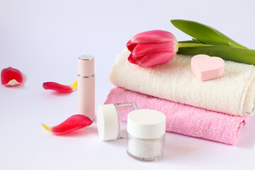 Scarlet tulip on terry towels, body care products, heart-shaped sponge on a white background, side view-the concept of taking care of your body