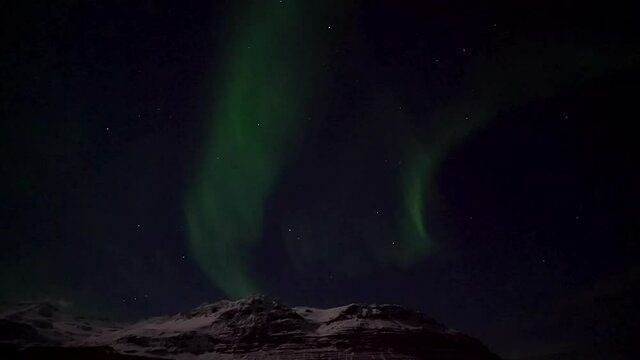 Northern Lights Rising Above Snow Capped Mountain in Iceland - real time video.