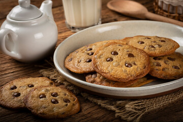 Delicious chocolate cookies with glass of milk on wooden table.