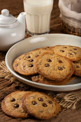 Delicious chocolate cookies with glass of milk on wooden table.