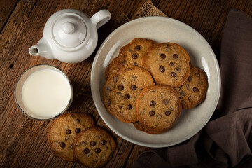 Delicious chocolate cookies with glass of milk on wooden table.