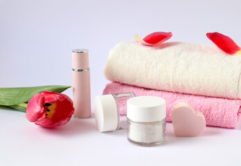 Pink and white terry towels, body care products, scarlet tulip on a white background, side view-the concept of taking care of your body
