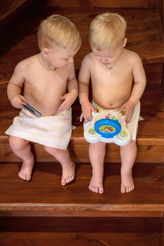 Twin boys relax in the sauna. Сute children in the sauna on a wooden shelf. Steam and heat in the Russian bath. Little boys play on the stairs in the Russian bath. Kids parody adults
