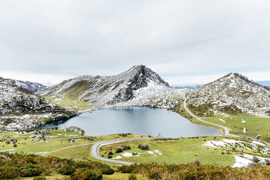 Spectacular view of rocky snowy mountain range near tranquil lake and spacious grassy valley in peaceful nature in Asturias