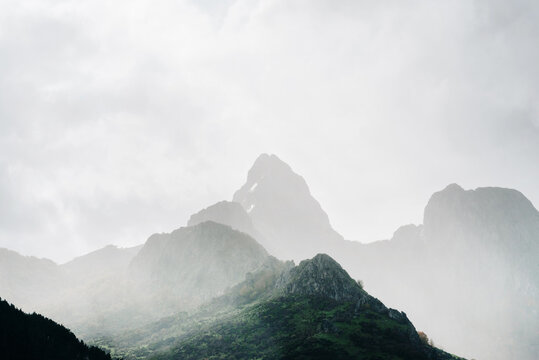Scenery of rocky rough mountain range peaks covered with dense mist on overcast day
