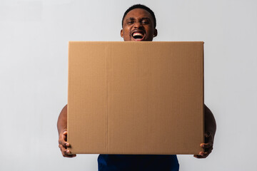 Delivery man holding a white T-shirt and blue pants with a box in his hands. Isolated on a white background. Concept of delivery, mail, shipment, loader, courier. Box close up