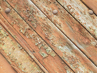 textured background of old time-worn wooden planks, set at an angle of 45 degrees, from a mixture of red, white and brown colors, siding of a wood panel of an old house, close-up, no people, patern. 