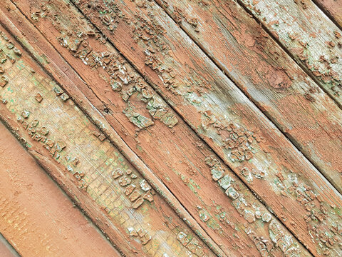 textured background of old time-worn wooden planks, set at an angle of 45 degrees, from a mixture of red, white and brown colors, siding of a wood panel of an old house, close-up, no people, patern. 