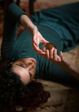 Relaxed female with black hair lying on carpet with transparent crystal ball in room with retro design