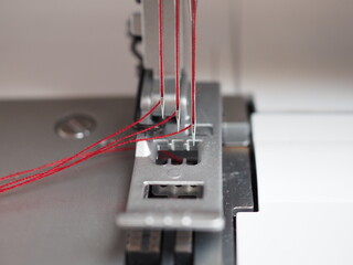 Die Nadeln einer Nähmaschine mit rotem Faden