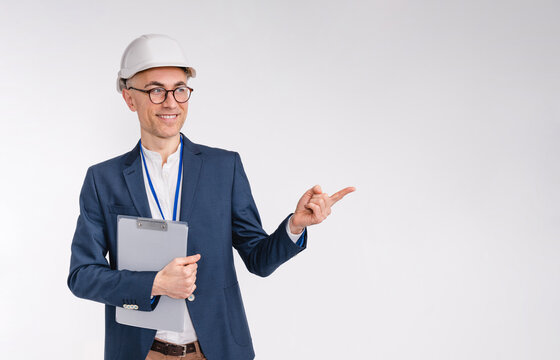 Handsome middle-aged white engineer in hardhat pointing at copy space isolated over white background - Powered by Adobe