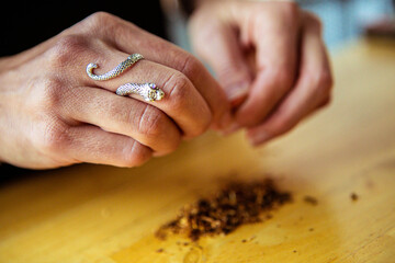Cropped hands cleaning dry tobacco at table