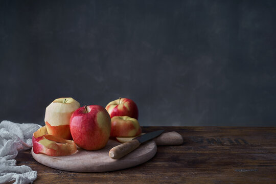 Fresh ripe whole and sliced red apples with cutting board and knife arranged on rustic wooden table