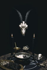 Witchcraft composition with goat skull, candles, magic book and pentagram symbol. Black magic and...
