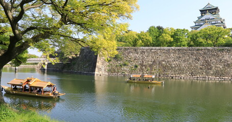 Fototapeta na wymiar Touristic boats with tourists along the moat of Osaka Castle one of best activities you can experience around Osaka Castle area, one of most famous landmarks of Japan