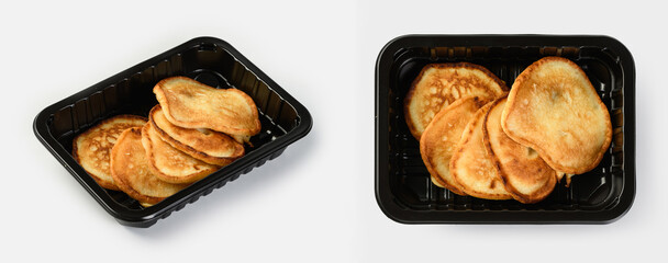 Pancakes in a black plastic container on a white background for delivery services
