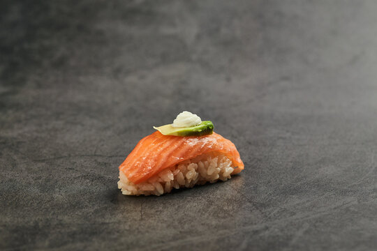High angle of palatable nigiri sushi with slice of salmon on rice topped with thin slice of avocado and cream cheese