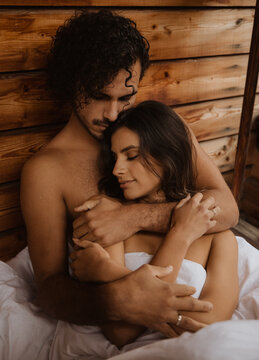 From above loving young couple bonding tenderly and lying with eyes closed on white soft blanket on wooden cottage terrace on autumn day