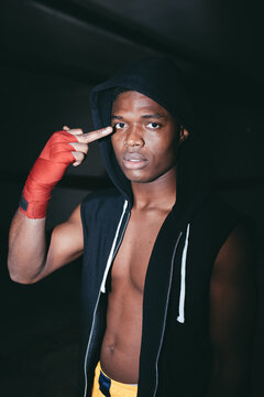 Young rude African American male athlete in hoodie demonstrating middle finger and looking at camera