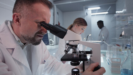 Diverse scientists studying medical samples. Using computers and microscopes. Modern laboratory interior