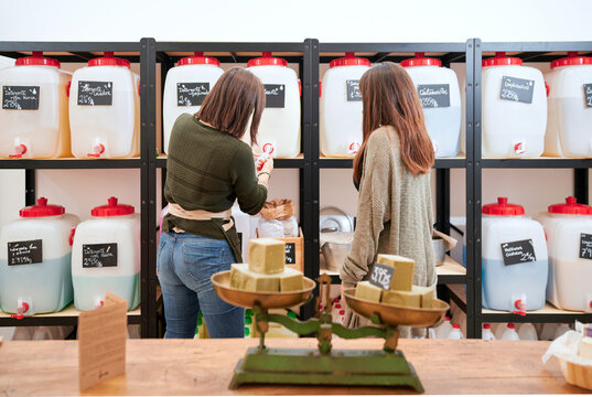 Back view of women selecting bottled cleaning agent placed on shelves in eco friendly store