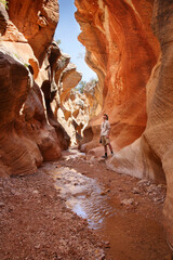 adult man standing in a slot canyon and looking upward
