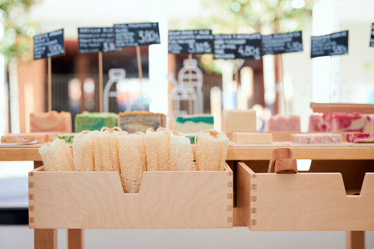 Various colorful handmade soap with tongs and price tags placed on wooden table in eco store