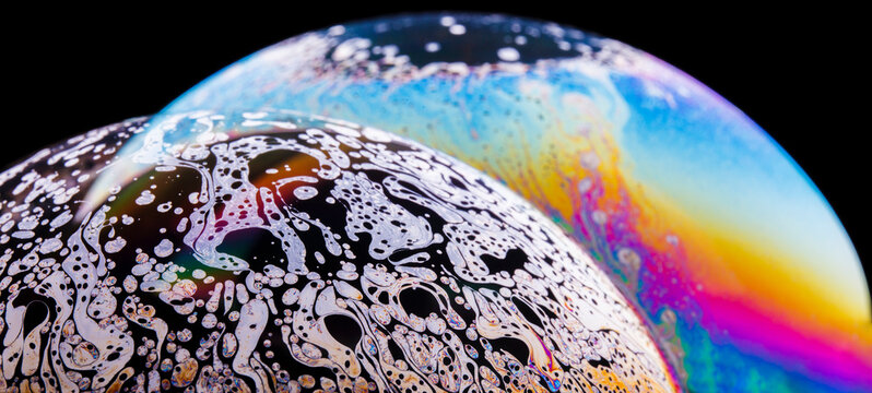 Panoramic view of closeup bubble textured backdrop representing colorful planets with wavy lines on round shaped surface on black background