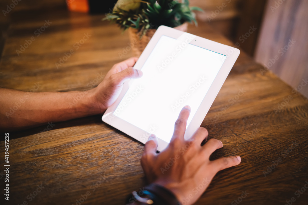 Poster cropped image of man typing on digital tablet with mock up screen chatting on web page in applicatio