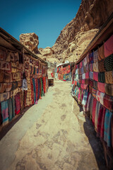 Fototapeta na wymiar Shopping street with market in the ancient city of Petra in Jordan with souvenir products, fabrics and carpets with national Bedouin ornaments