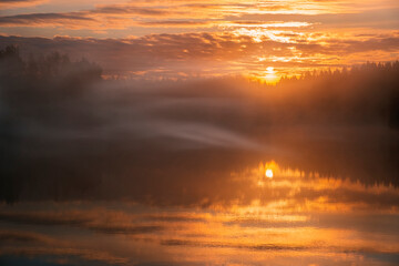 Fototapeta na wymiar misty orange sunrise over lake, soft focus