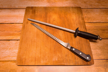 wooden cutting board with a ham or salmon knife and a sharpening gun