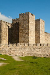 Towers and stone walls facade with merlons on a cloudy day at the Castle of Trujillo.