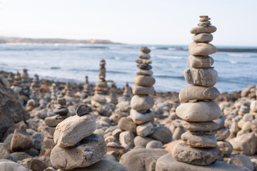 Picturesque scenery of zen stone pyramids created in beach near waving ocean on sunny day in Vila Nova de Milfontes, portugal